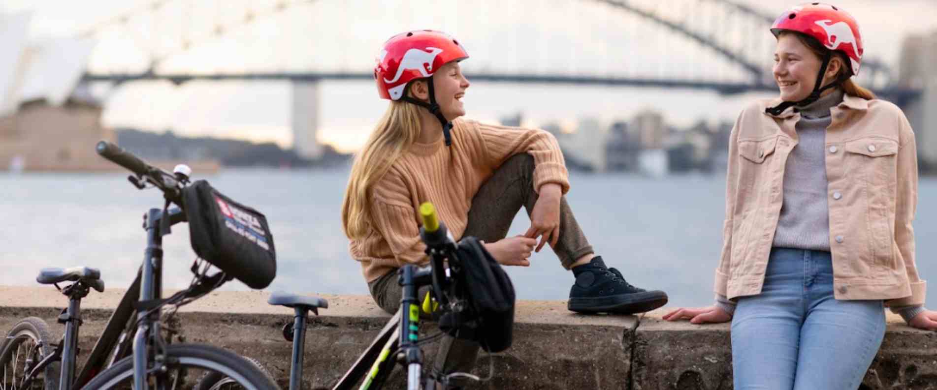 Two girls sitting on wall with bikes