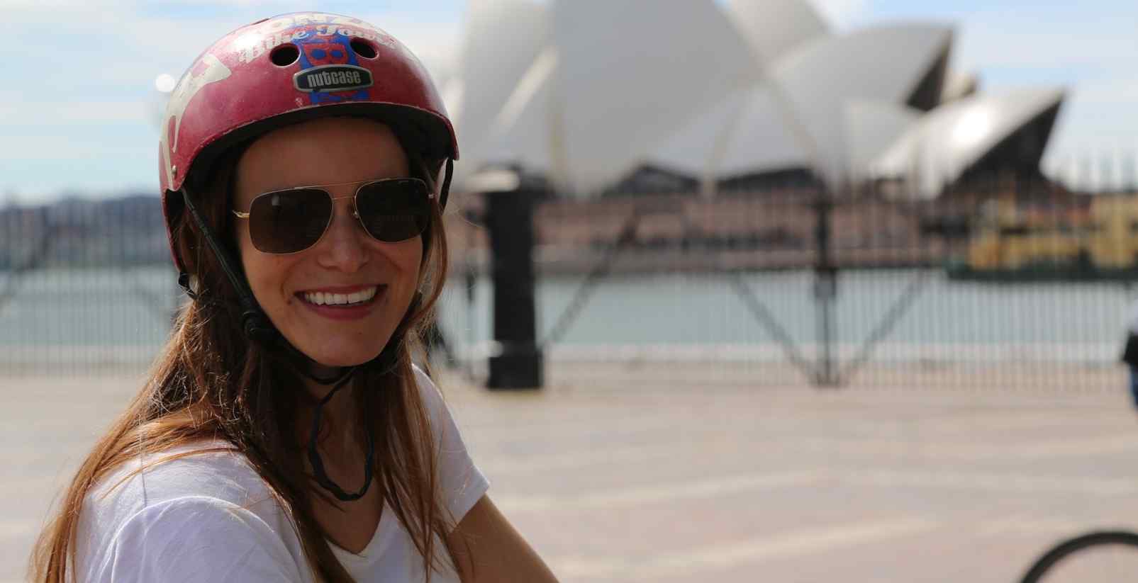 woman smiling with helmet in front of Opera house